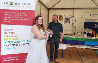 zwei Aktive von QueerNet Rheinland-Pfalz vor ihrem Infostand